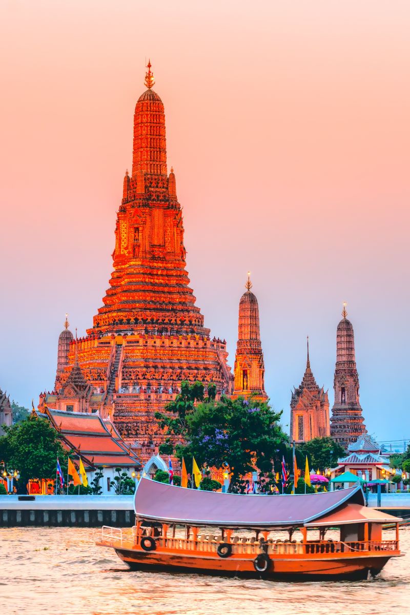 small ferry boat afloat in front of Asian temple